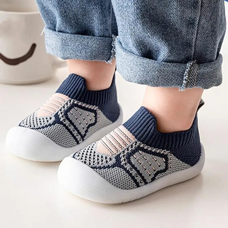 A pair of navy and beige breathable anti-slip baby first walker shoes worn by a child.