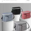 A collection of four fabric stroller organizer bags in shades of gray, black, and pink are displayed on white pedestals.