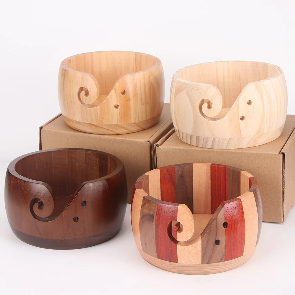 Three handcrafted wooden yarn bowls with swirl cutouts displayed on cardboard boxes.
