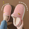 A pair of pink faux fur slippers being held, showing the plush exterior and soft lining.