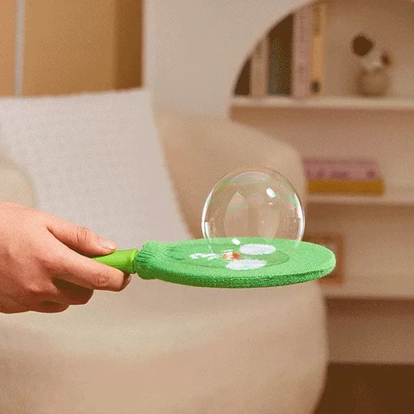 A hand holds a green smoke bubble wand with a clear bubble on the tip.