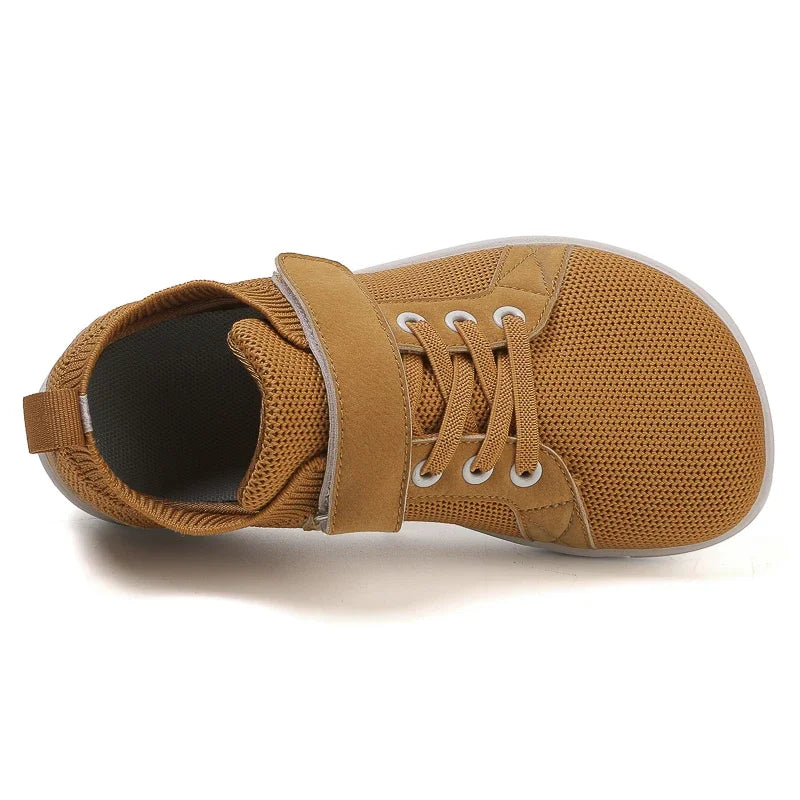 A side view of tan kids barefoot training sneakers with a wide toe box and light gray sole.