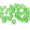 A pile of faceted green bicone crystal glass beads for jewelry making.