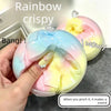 A hand is squeezing a pink and yellow squishy toy that makes a sound.