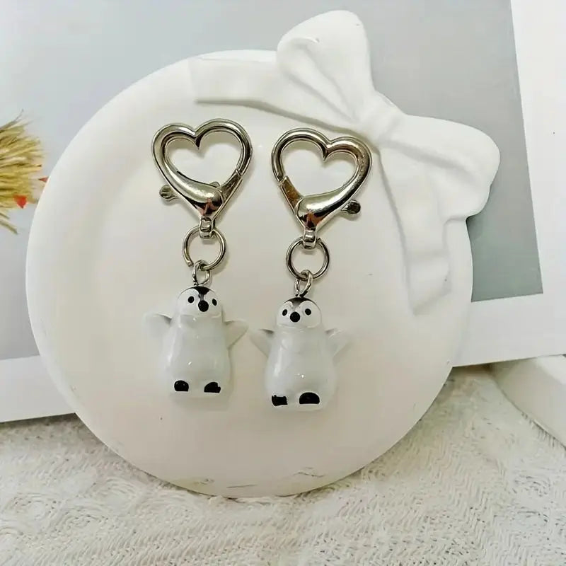 A silver heart keychain set featuring two white penguin charms.