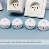 A set of white rotating socket safety covers for baby proofing, shown next to an electrical outlet.