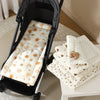 Matelas en coton doux blanc pour poussettes bébé, à côté d'un cadre de poussette noir.