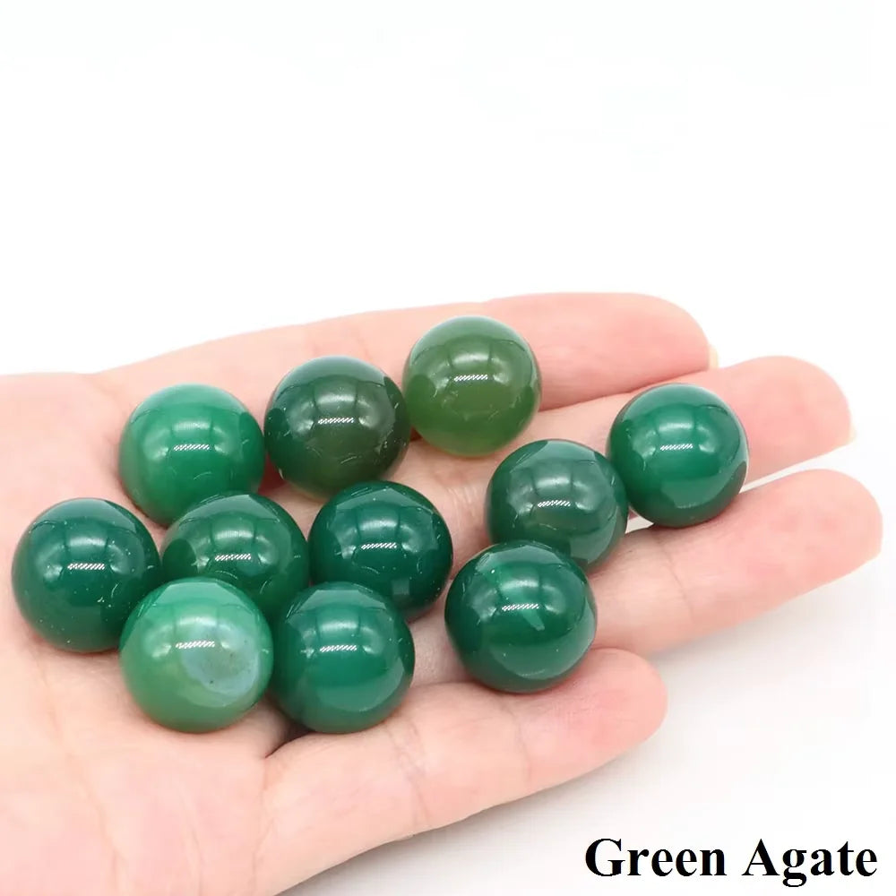 A hand holds several polished green agate crystal spheres.