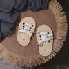 A pair of wooden lacing shoes toy resting on a burlap mat with fringe.