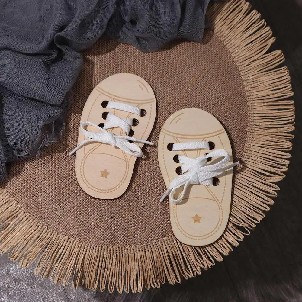 A pair of wooden lacing shoes toy resting on a burlap mat with fringe.