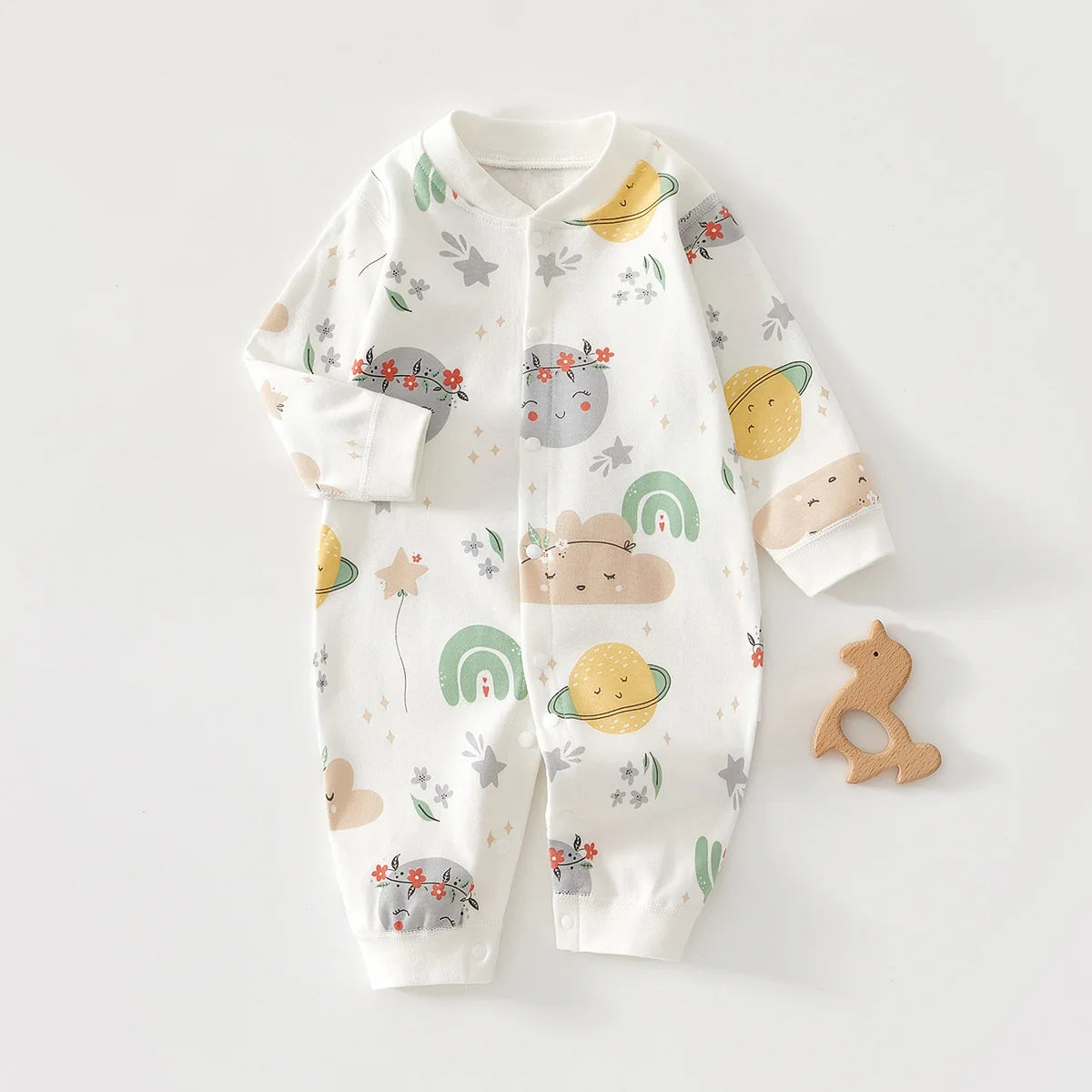 A white cotton long sleeve baby romper featuring scattered illustrations of yellow fruit, leaves, and rainbows.