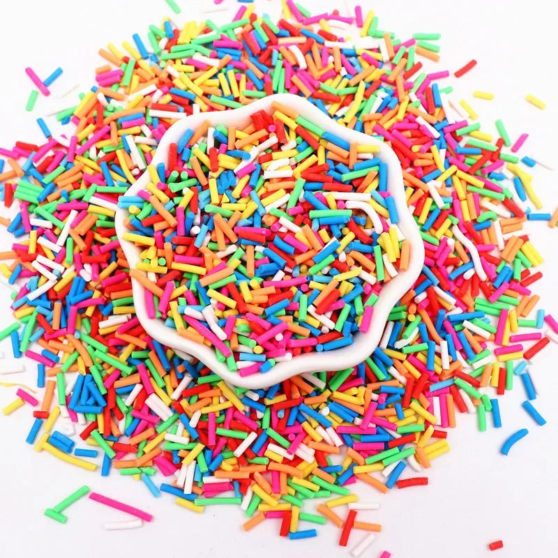 A pile of multi-colored polymer clay sprinkles mixed with white sprinkles in a decorative mold.