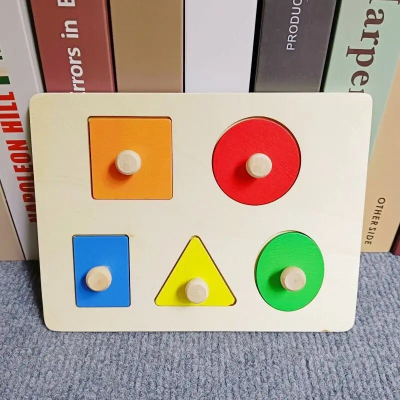 A wooden shape and color sorter puzzle featuring four colored shapes: orange square, red circle, blue square, and green circl