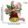 A hand-stitched embroidery of a festive cartoon character bell with green leaves and pink ribbon.