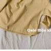 A light yellow long sleeve cotton tee laid flat on a white surface.