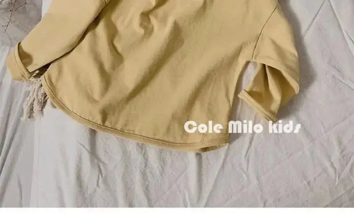 A light yellow long sleeve cotton tee laid flat on a white surface.