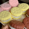A collection of realistic cake squishy fidget toys in various colors including pink, yellow, and brown.
