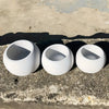 A set of three white silicone round pot molds resting on a rough concrete surface.