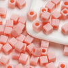A pile of square pink acrylic spacer beads for DIY jewelry making