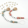 A necklace featuring silicone teething beads and a pacifier clip, with a scattering of wooden stars in the background.