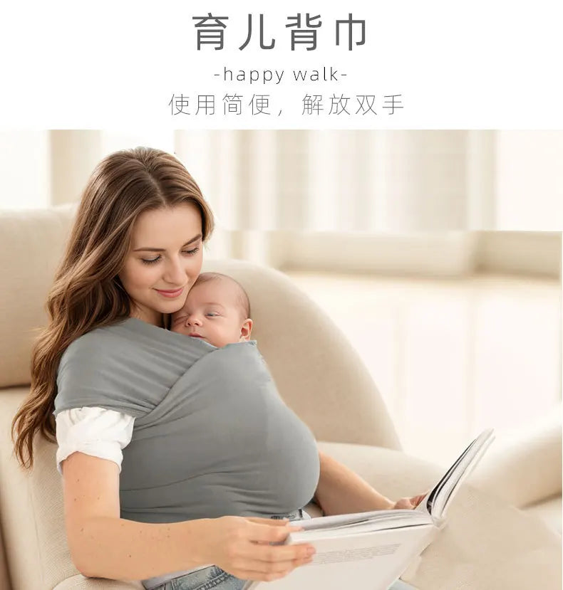 A woman is holding a baby in an ergonomic sling carrier while reading a book indoors.