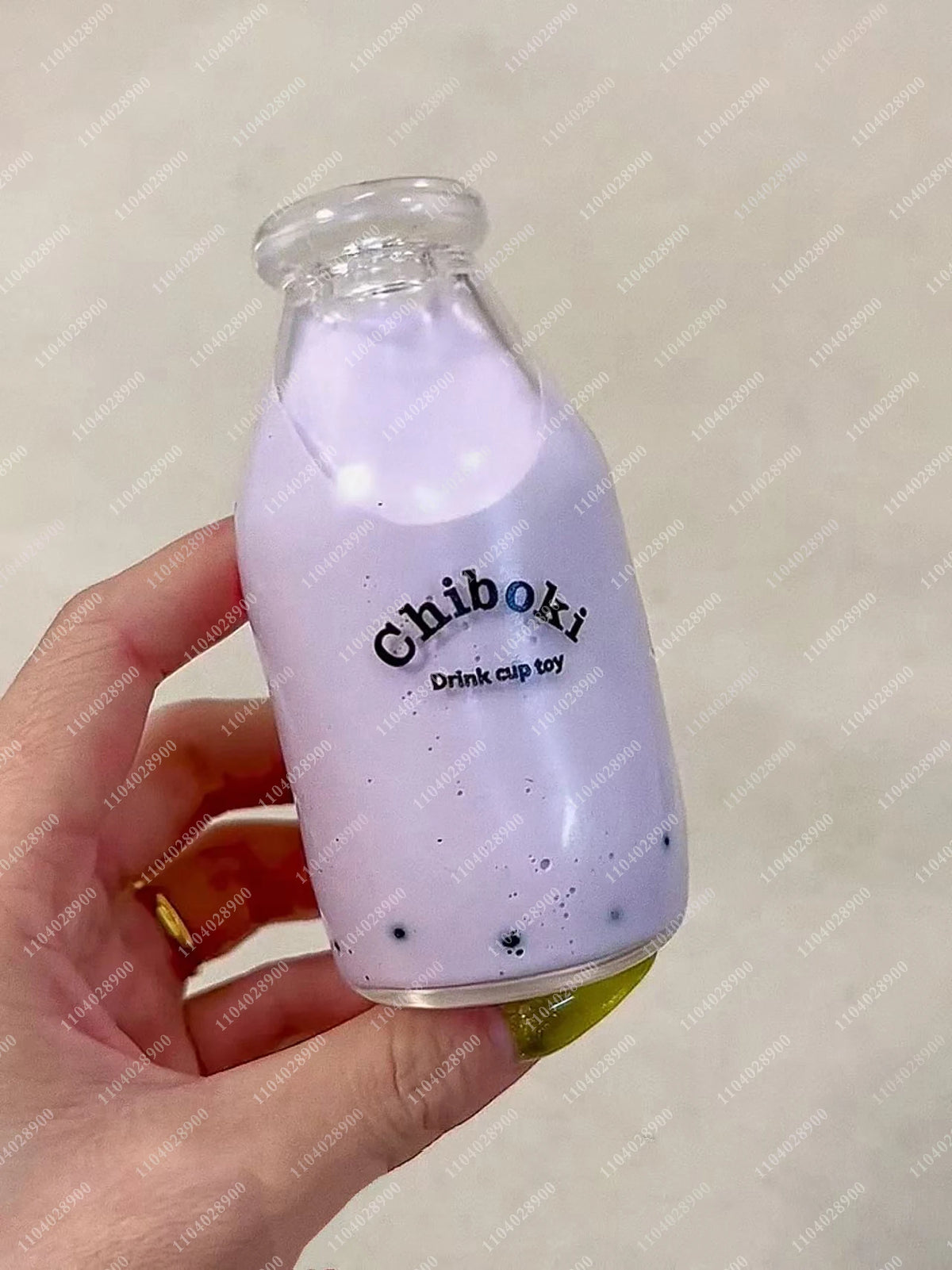 A purple squishy milk bottle stress ball is held in a hand against a light background.