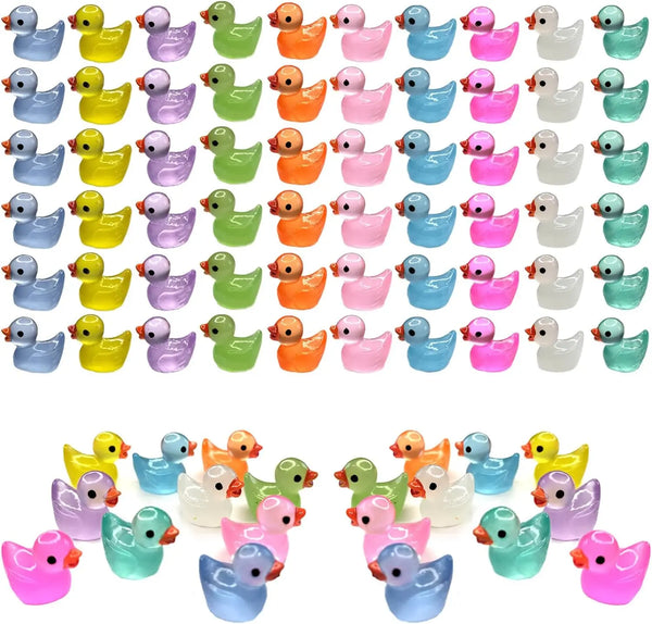 A collection of glow in the dark miniature duck figurines in various colors and shapes.
