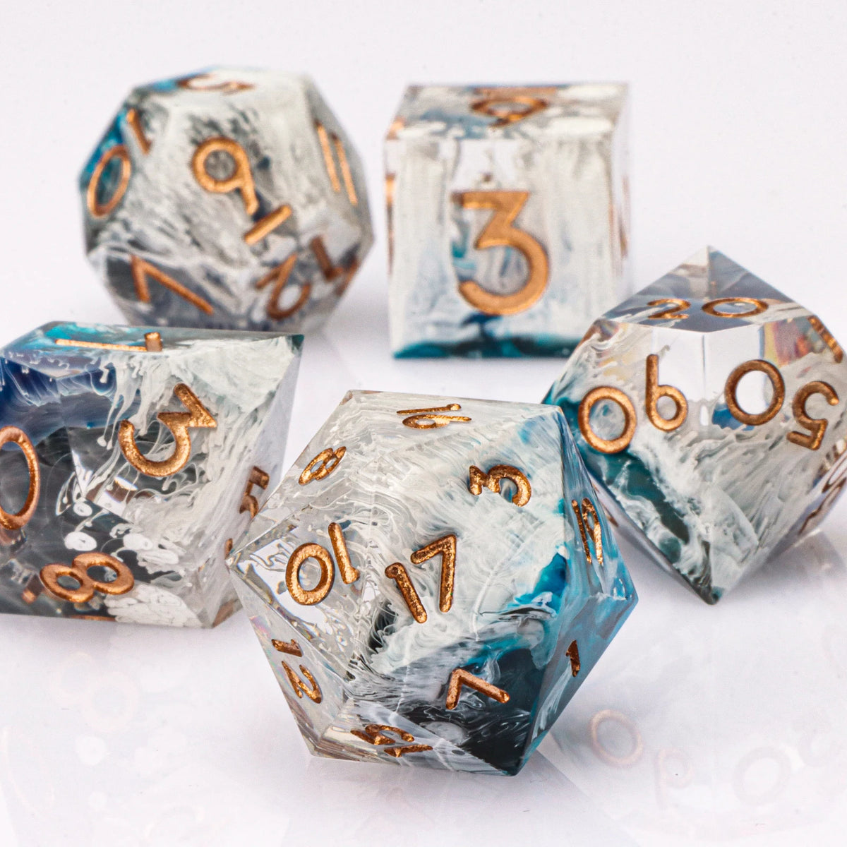 A collection of handmade resin polyhedral dice in various colors and angles resting on a white surface.