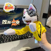 A yellow plush toy resembling a stylized wolf or dog character is positioned in front of an open laptop.