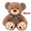 A brown teddy bear plush pillow with a plaid bow and large paws.