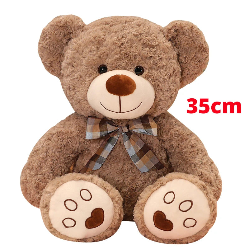 A brown teddy bear plush pillow with a plaid bow and large paws.