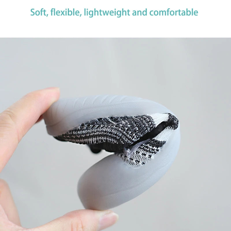 A hand holds a gray toddler walking shoe with black mesh detailing on the sole.