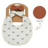 A white fabric bib with a rainbow pattern and a matching brown bow headband shown next to its packaging.