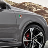 A close-up of a gray SUV featuring a 3D chrome Mexican flag emblem decal on the hood and a black alloy wheel.