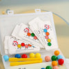 An open box of wooden caterpillar clip beads for a Montessori fine motor skills game with various colored beads and yellow st
