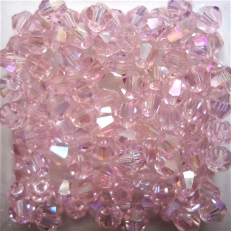 A pile of faceted pink glass bicone beads for jewelry making.