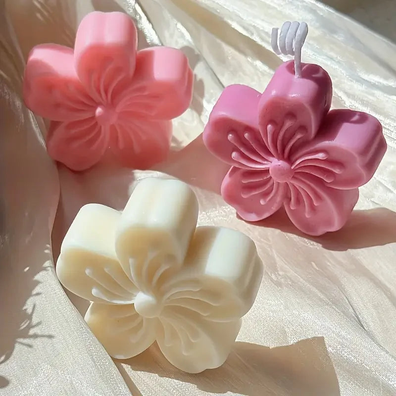 Pink and white silicone flower molds for soap, candle, and craft making displayed on a light surface.