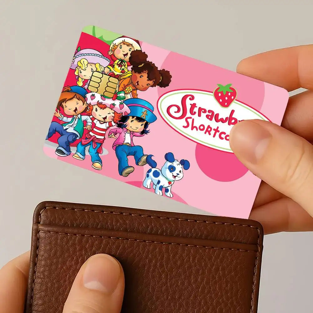 A hand holds a pink card featuring Strawberry Shortcake cartoon characters and a strawberry design.