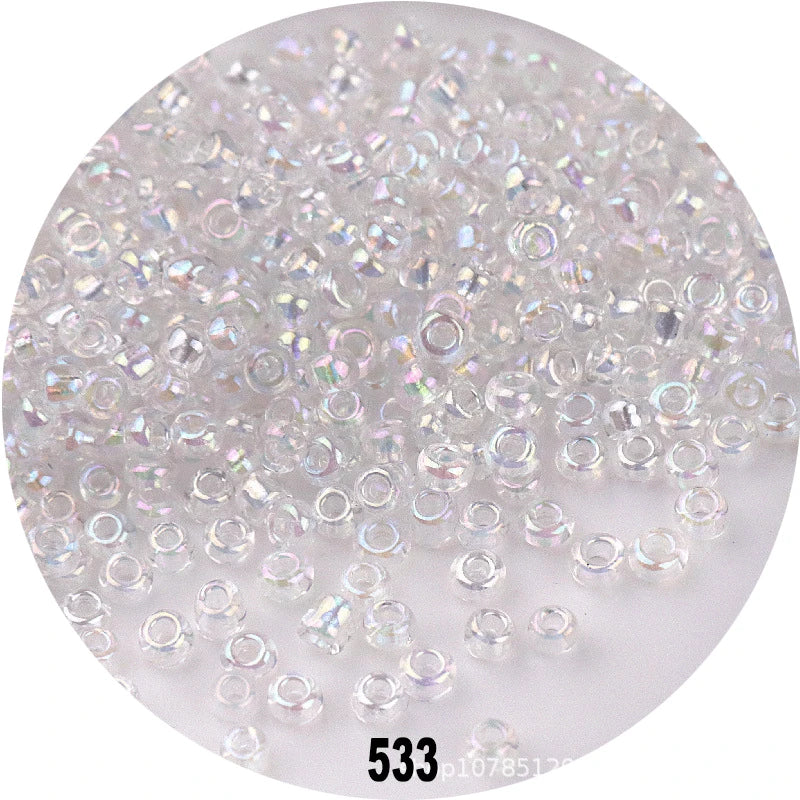 A close-up view of clear and colorful round glass seed beads scattered on a white surface.