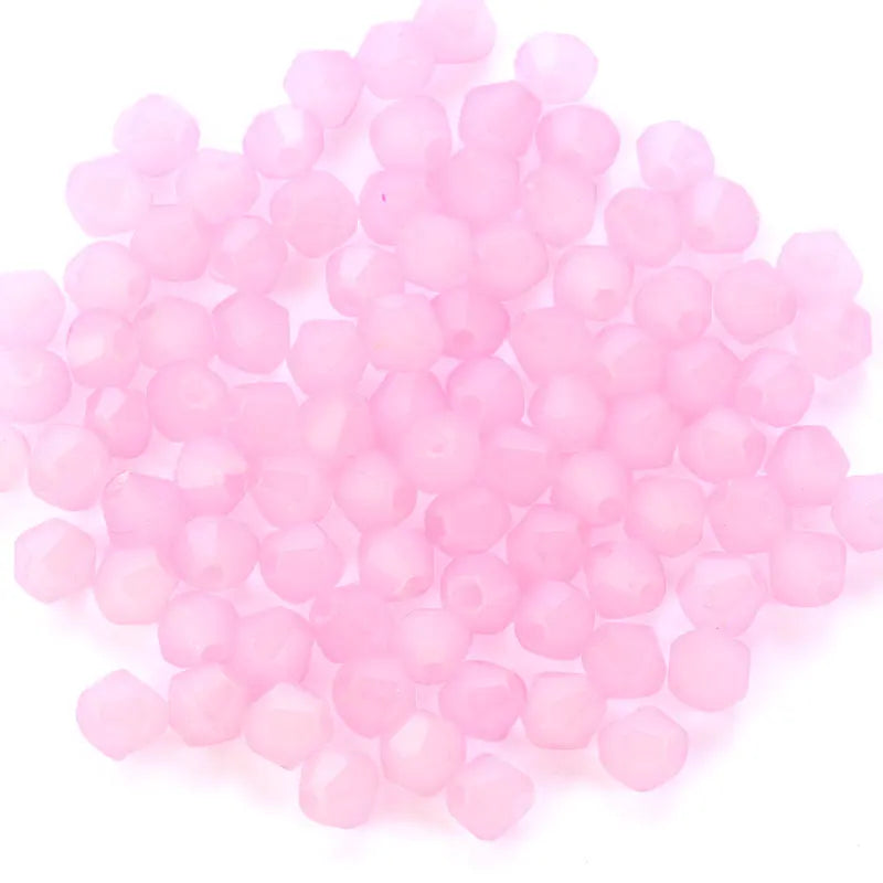 A pile of small, round, faceted pink glass beads for jewelry making.