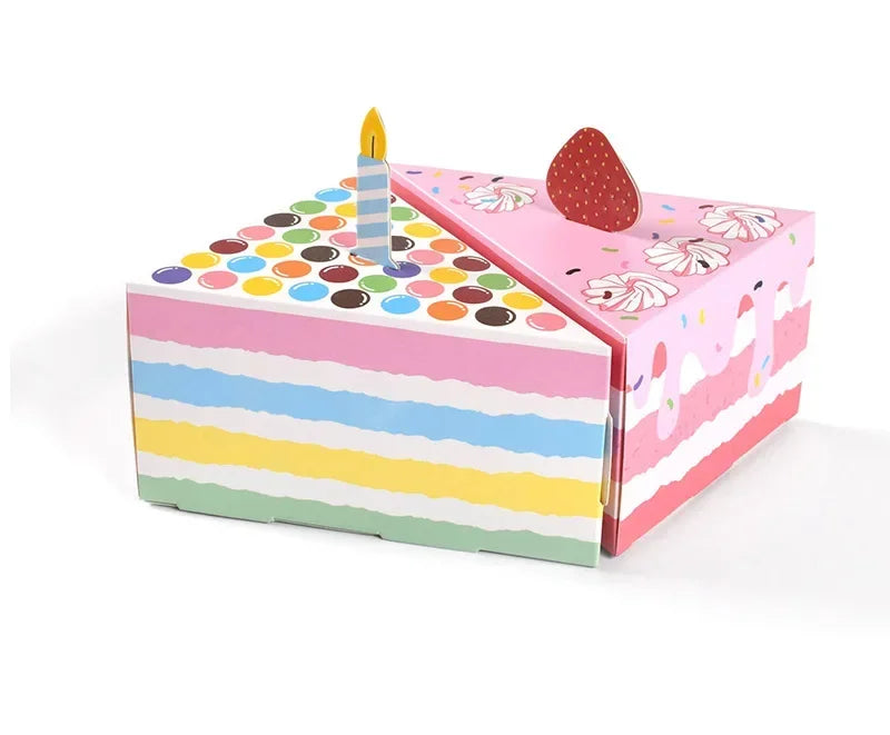 A pink and multicolored gift box with a lid open, featuring a candle and dot-shaped paper decorations.