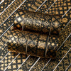 A set of 20 rolls of black and gold foil washi tape arranged diagonally on a patterned surface.