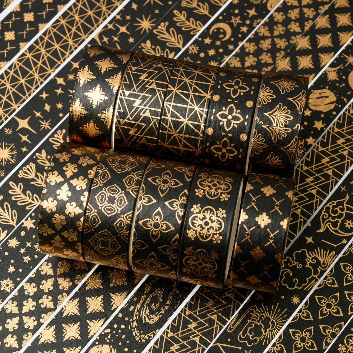 A set of 20 rolls of black and gold foil washi tape arranged diagonally on a patterned surface.