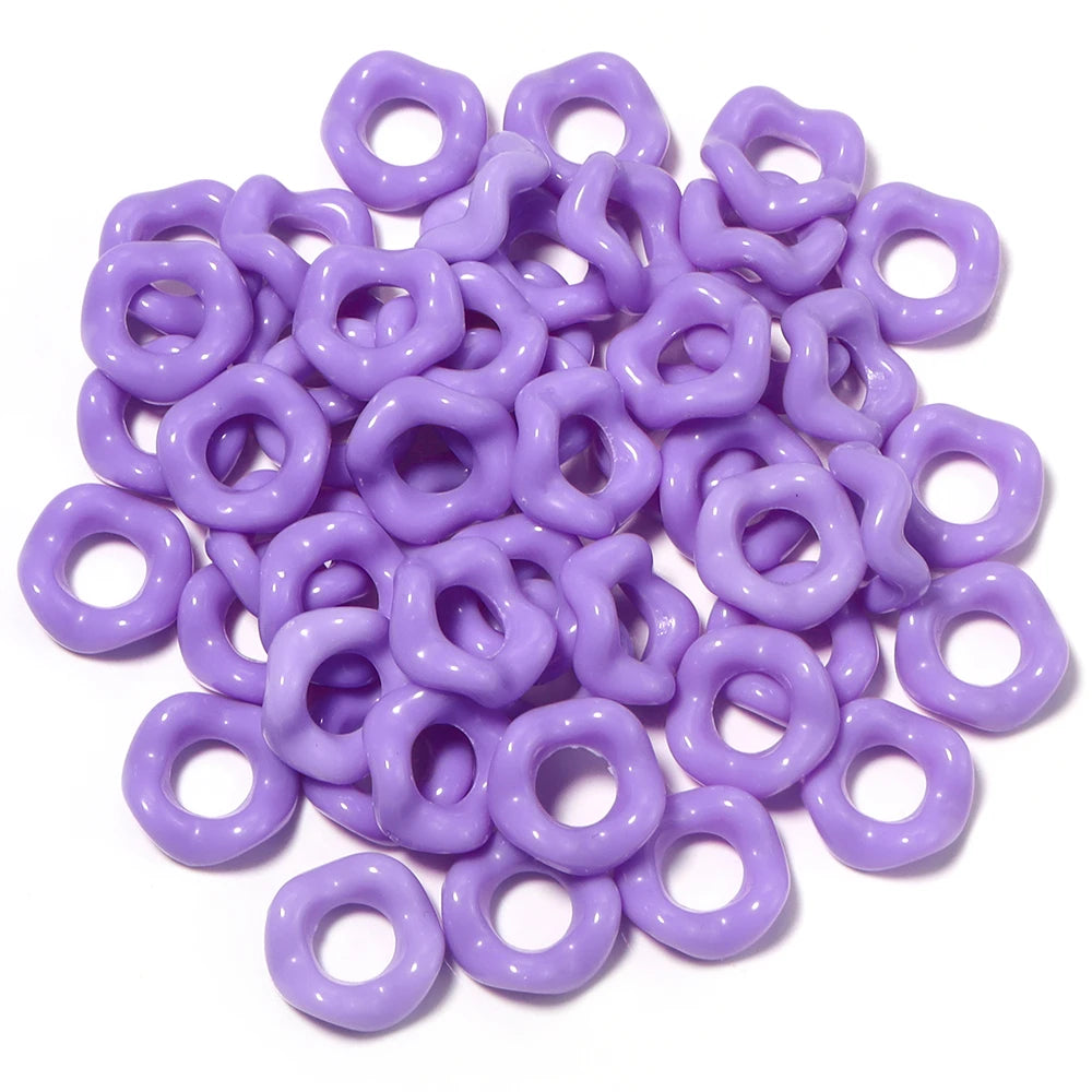 A pile of purple acrylic doughnut spacer beads for jewelry making