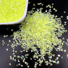 Bright yellow crushed glass crystals scattered on a dark surface.