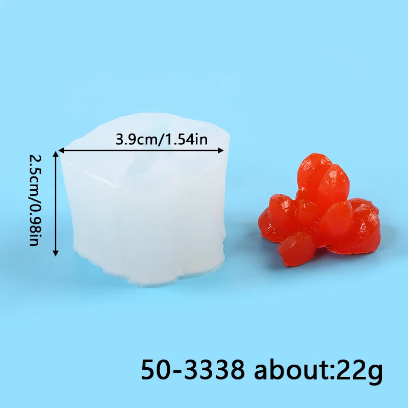 A white silicone mold shaped like a cactus or succulent, next to several small, red, spherical objects.