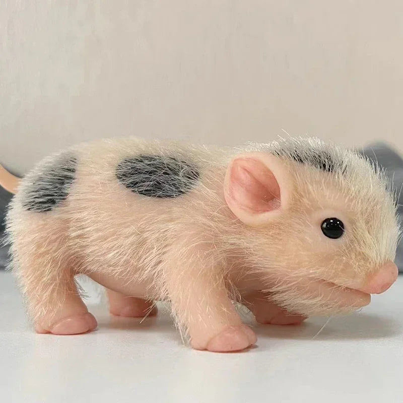 A small, light pink silicone reborn piglet doll with gray spots is shown in a side view.