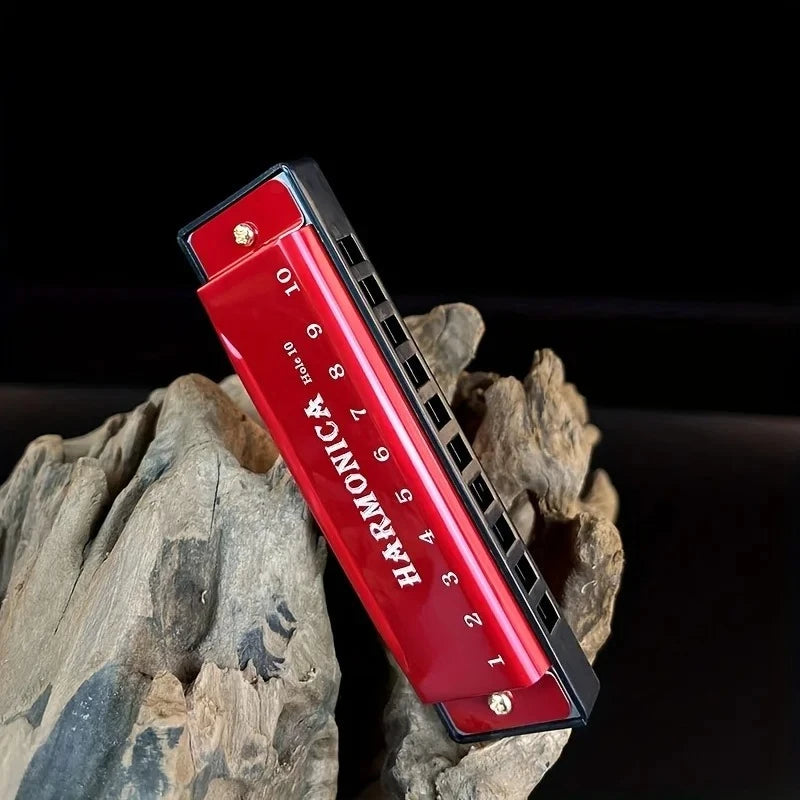 A red 10-hole diatonic harmonica with a black carrying case rests on a piece of weathered wood.