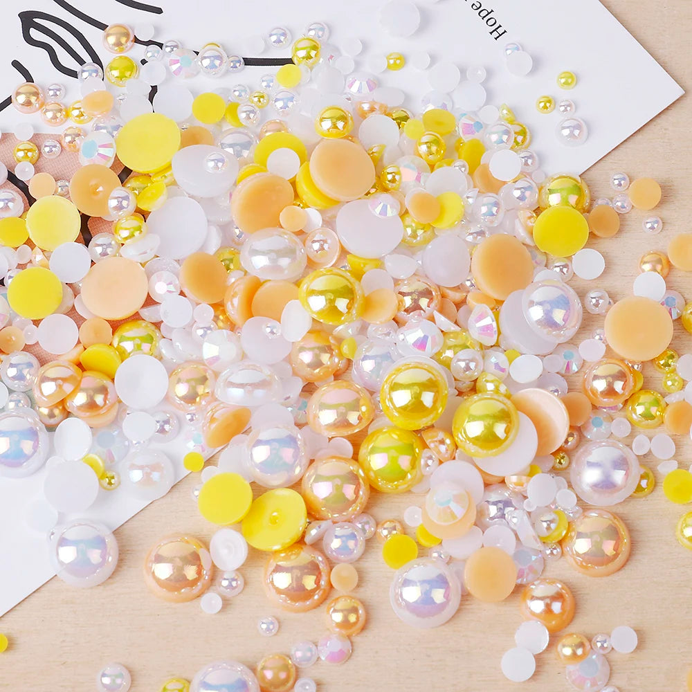 A scatter of mixed resin rhinestone pearls in yellow, gold, and iridescent finishes for craft and nail art.
