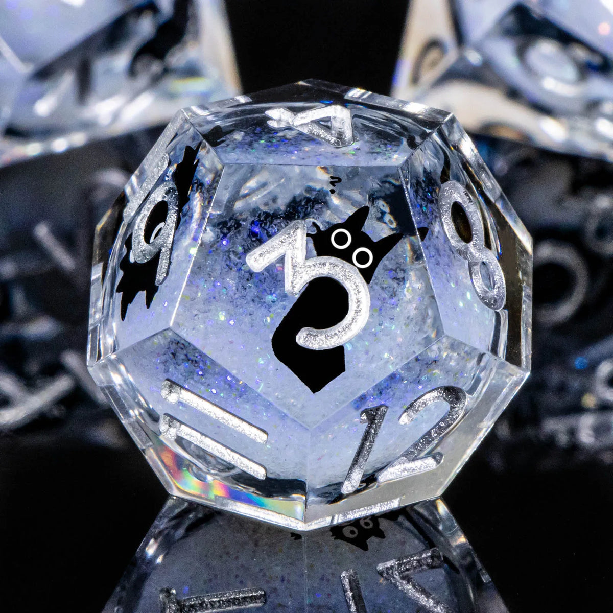 A clear, faceted resin die with the number 5 and a cat silhouette engraved on its surface.